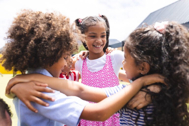 In school, diverse group of young students hugging, laughing outside